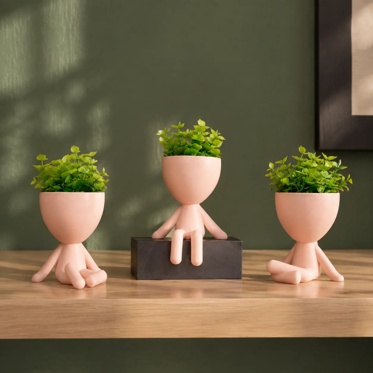 Três mini vasos rosa-claro com plantas artificiais sobre aparador
