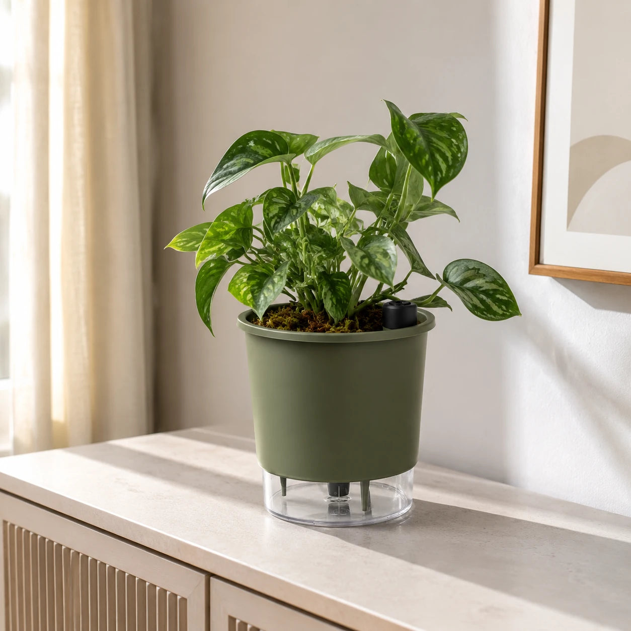 Vaso autoirrigável verde militar com folhagem em ambiente interno iluminado